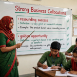 Teacher explaining strong business collocations on a classroom whiteboard with examples for professional English communication